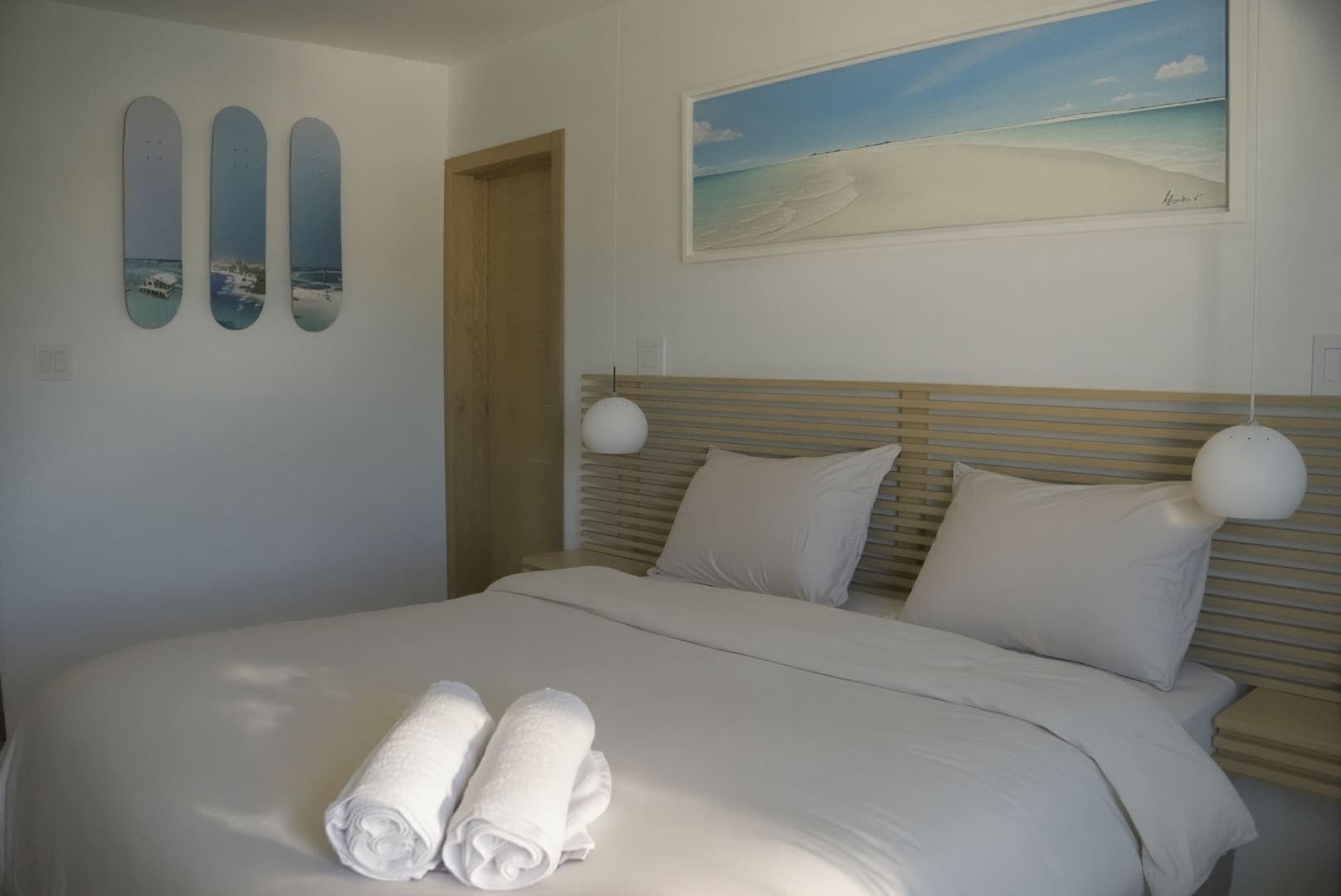 Habitación con cabecero de madera, lámparas de globo y un cuadro de la playa